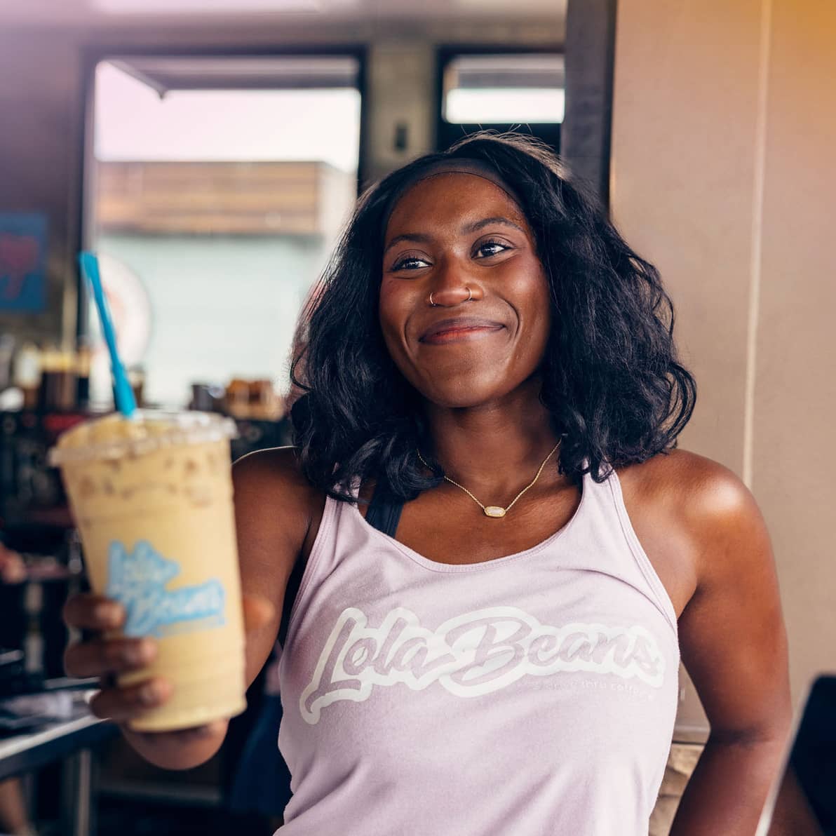 lola-drink-hold Guest sipping a layered green and orange drink with the LB mark on the cup